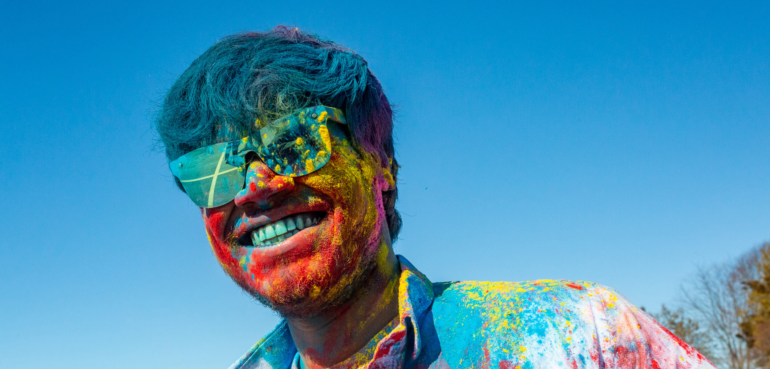 A student covered in colourful powder celebrating Holi
