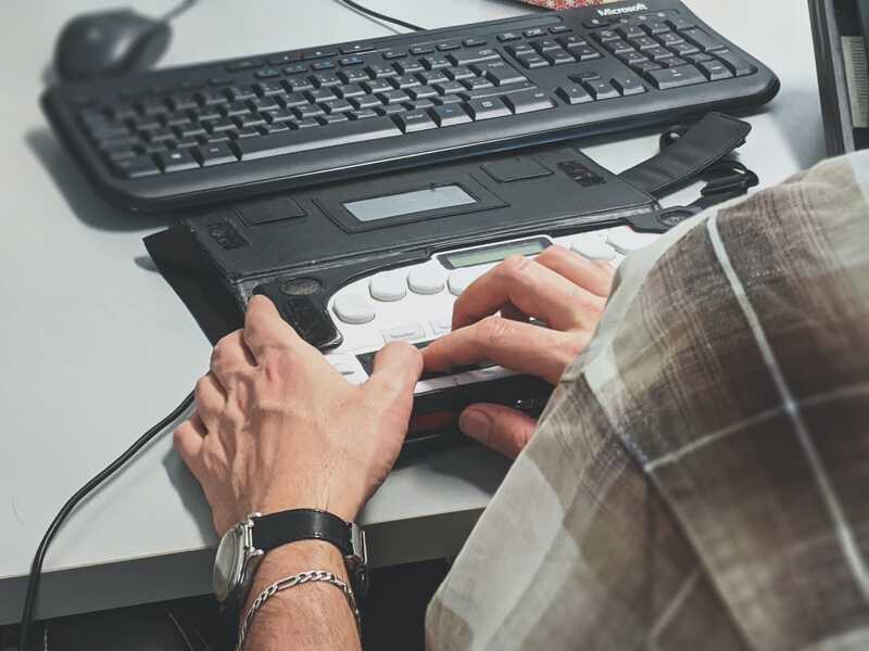 A man uses a screen reader that converts information into braille using electronically-controlled plastic pins.