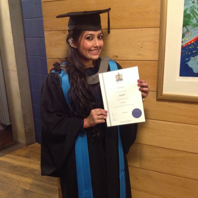 Woman in graduation ceremony cap and gown holding diploma