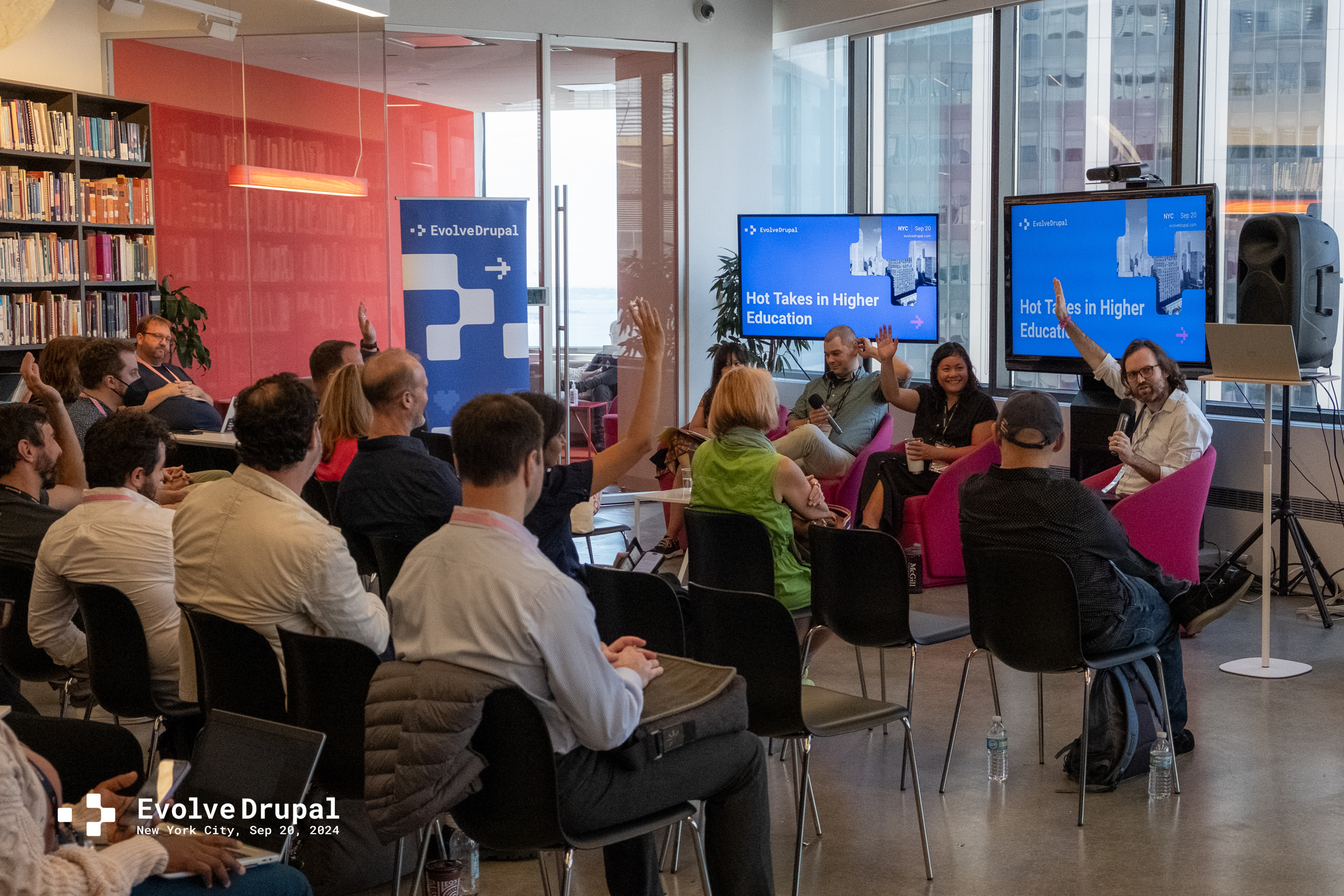 A conference room where panelists ask for a show of hands.