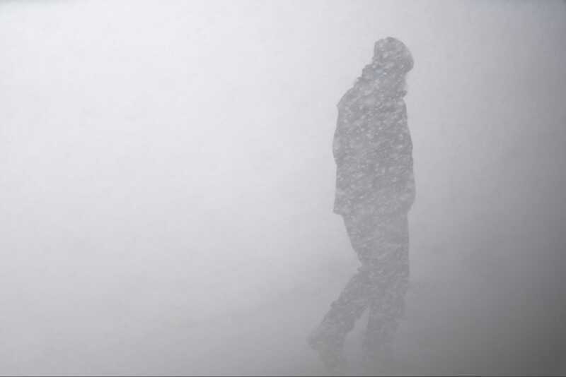 Alt text: A person walks through a snowstorm.