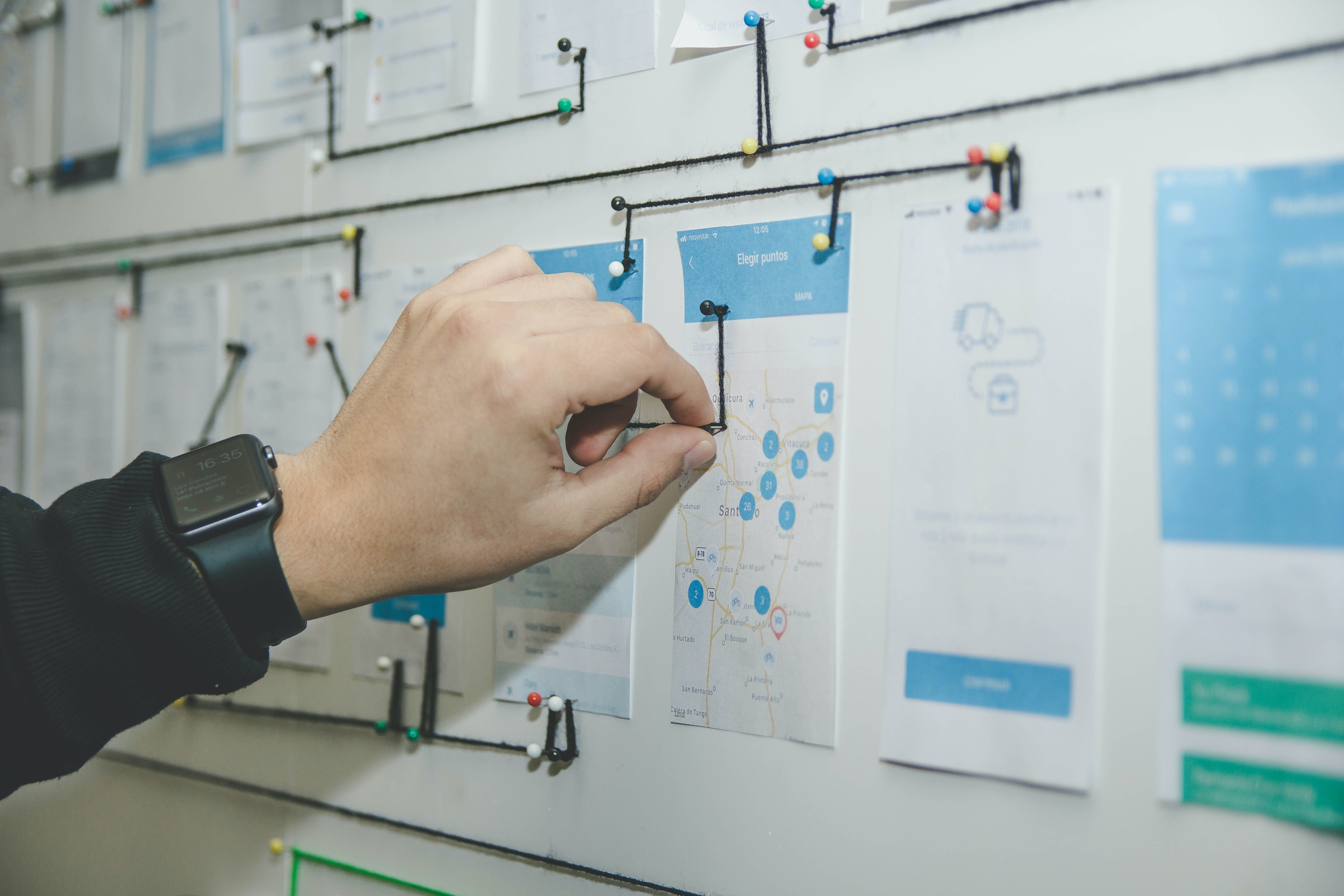 A hand moving an element on a whiteboard with wireframed design elements for a website