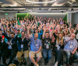 A picture of a crowd of people seated with their arms up