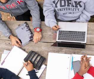 Aerial view of students and laptops on table outside.