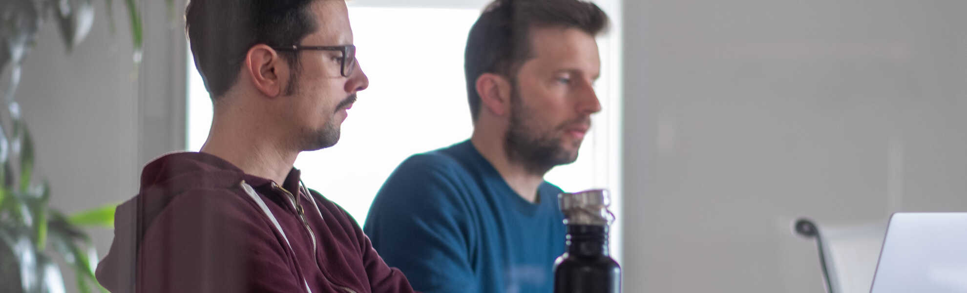 deux hommes sont assis et regardent un écran d'ordinateur
