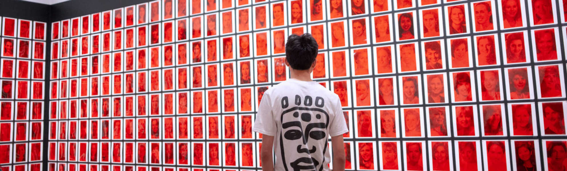 A person looking at a wall full of red art work