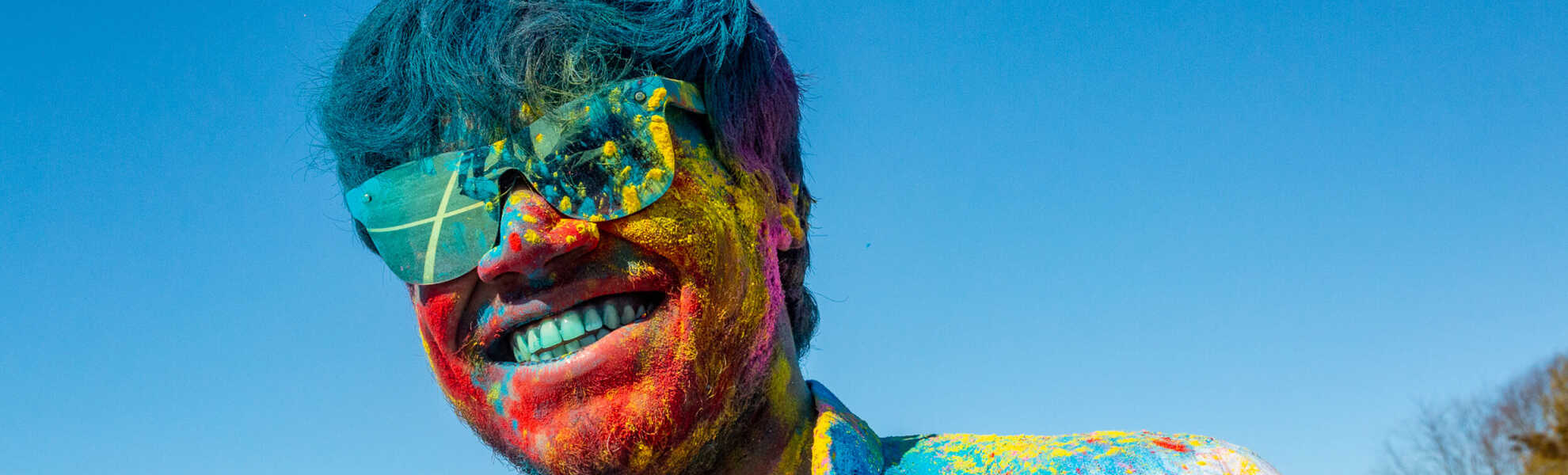 A student covered in colourful powder celebrating Holi