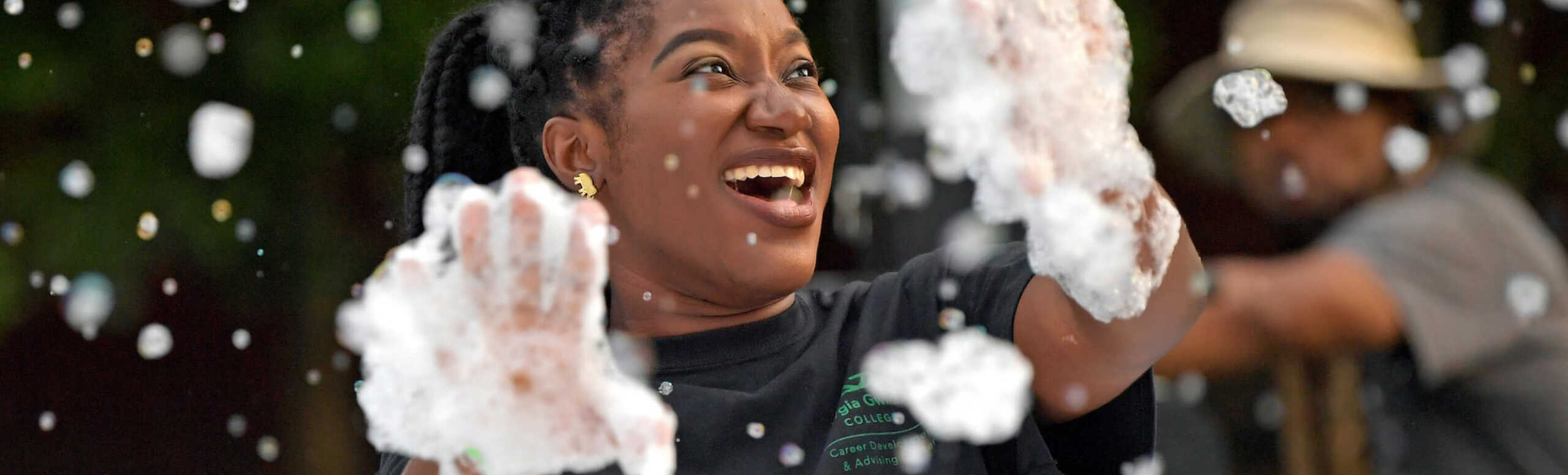 A GGC student is laughing and covered in bubbles