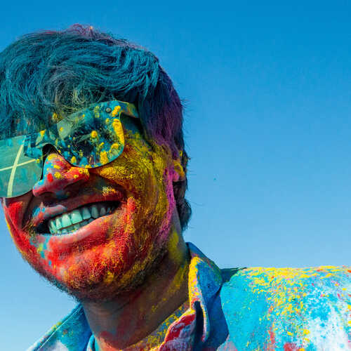 A student covered in colourful powder celebrating Holi