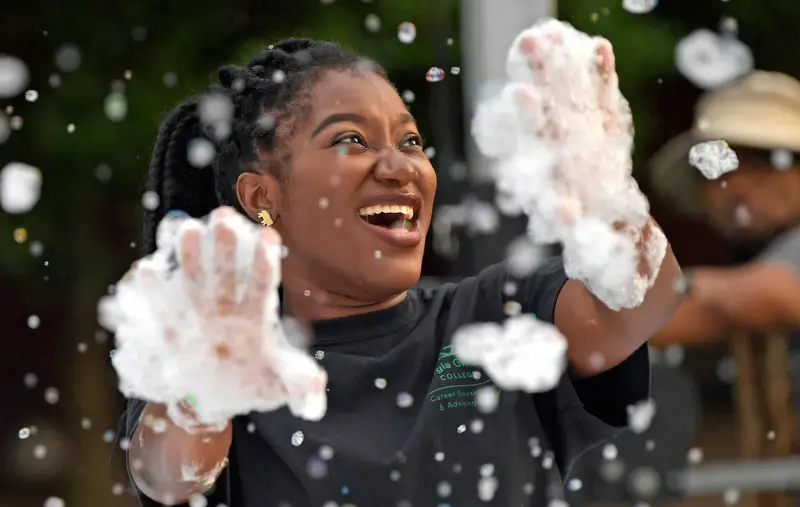 A GGC student is laughing and covered in bubbles