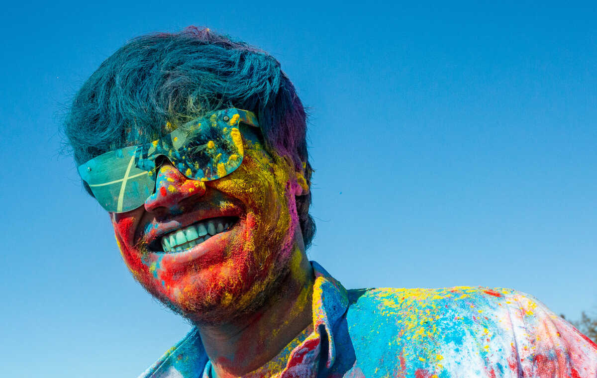 A student covered in colourful powder celebrating Holi